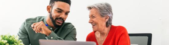 Two people smiling and looking at a computer screen.